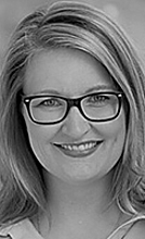 Porträt einer lächelnden Frau mit Brille und langen, glatten Haaren. Der Hintergrund ist unscharf, was den Fokus auf ihr freundlich strahlendes Gesicht lenkt.